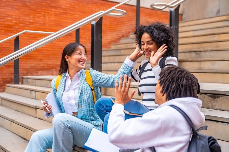 Happy multi-ethnic students sitting in the campus having fun relaxed after class in the university