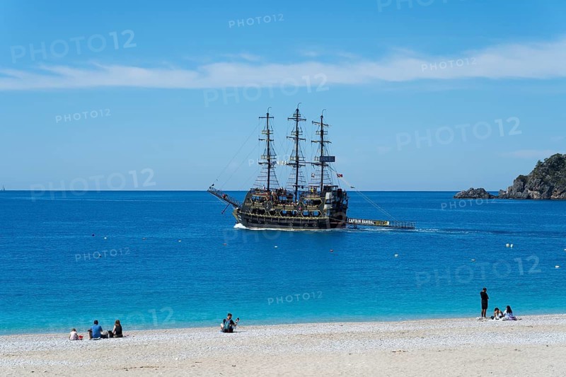 A pirate ship sails off a quiet beach in the blue sea under clear skies, Ölüdeniz, Fethiye, Mugla, Aegean Sea, Turkey