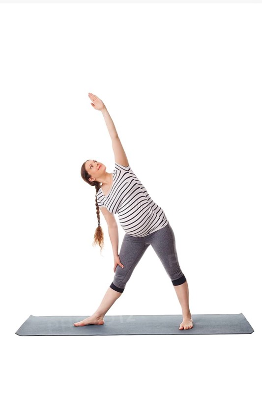 Pregnancy yoga exercise, pregnant woman doing asana Utthita trikonasana, extended triangle pose easy variation isolated on white background