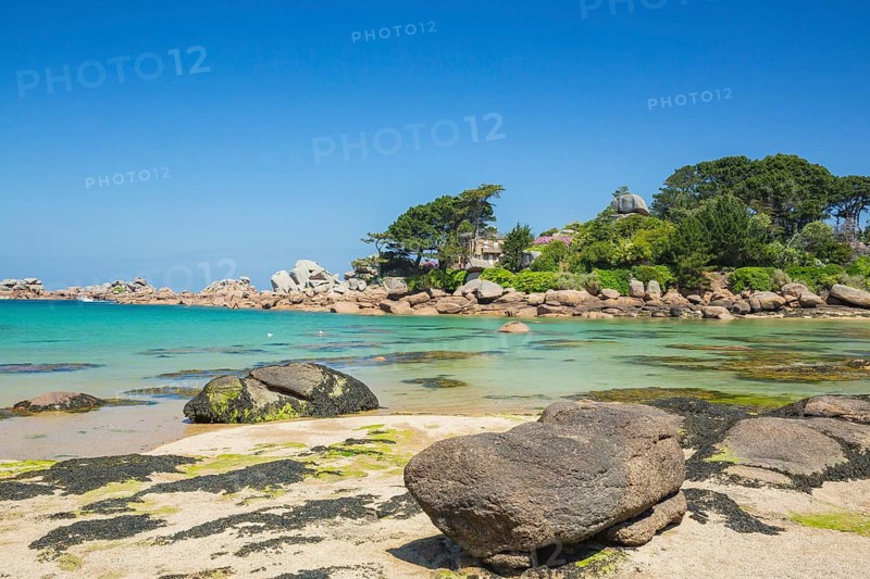 Beach with rocks and sand at the Plage Saint Guirec, with clear blue sky and colors as in the carribians