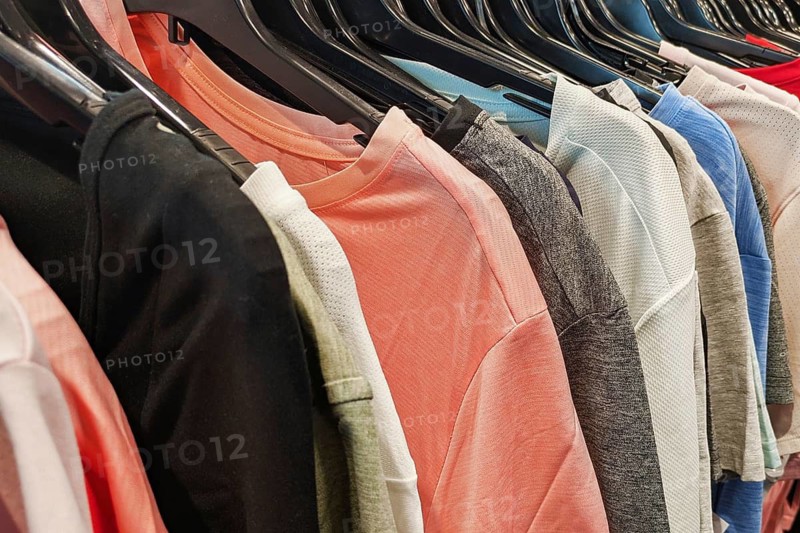 Heidelberg, Germany - 19th March 2026: Various tops and T-shirts in different colors and styles displayed on a clothing rack in a store
