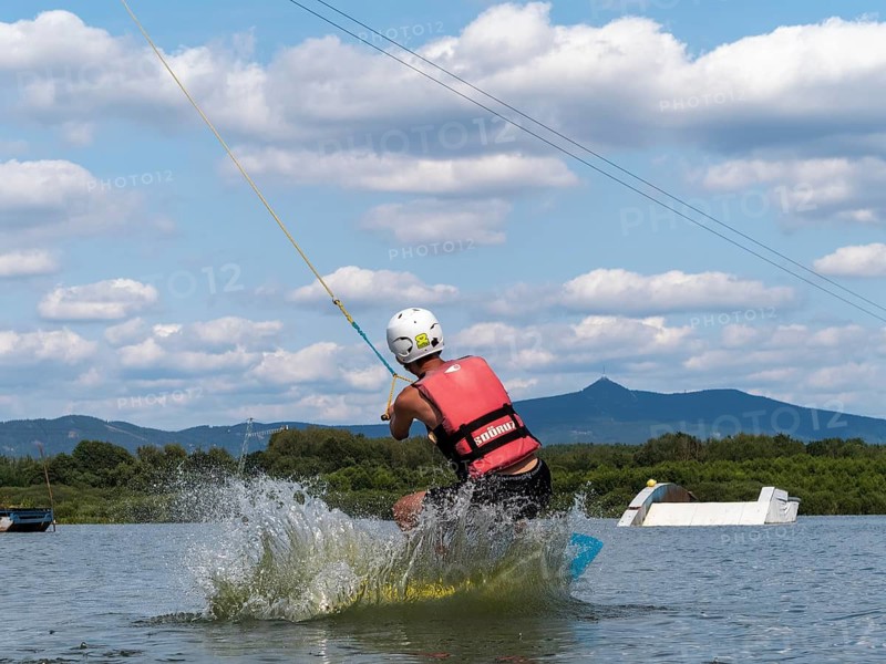Young man jumping into the water with a wakeboard, water ski and wake park, Stráž pod Ralskem, Jizera Mountains, Czech Republic