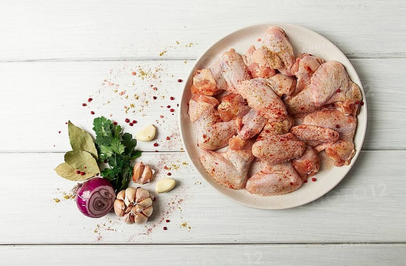 Fresh, raw chicken wings, with spices, on a white wooden table