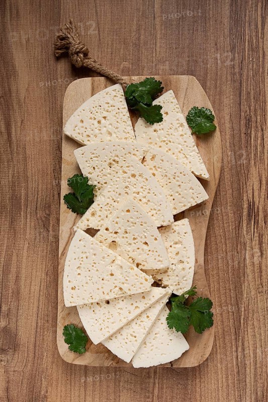 Sliced Georgian cheese, factory grade, on a wooden board, top view