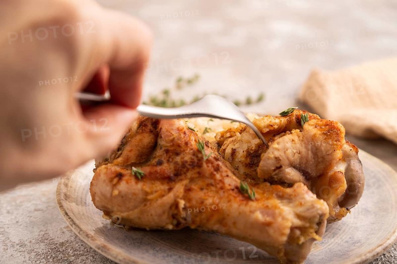 Fried Turkey Wing with spices and rice with hand on brown concrete background and linen textile. side view, close up, selective focus