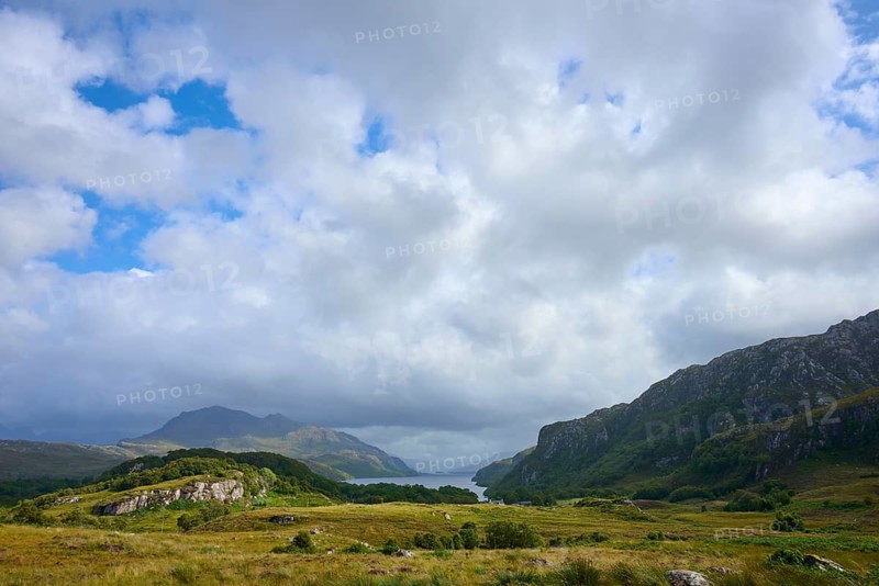 Wide grassland with view of distant mountains and clouds covering the sky, Loch Maree, Taagan, Achnasheen, Scotland, United Kingdom, Great Britain