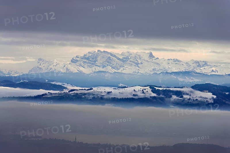 Fog over Lake Zug in the foreground the village of Cham, behind the snow-covered Alps with the Flübrig and Vrenelisgärtli mountains. Beinwil, Freiamt, Horben, Lindenberg, Canton of Aargau, Switzerland