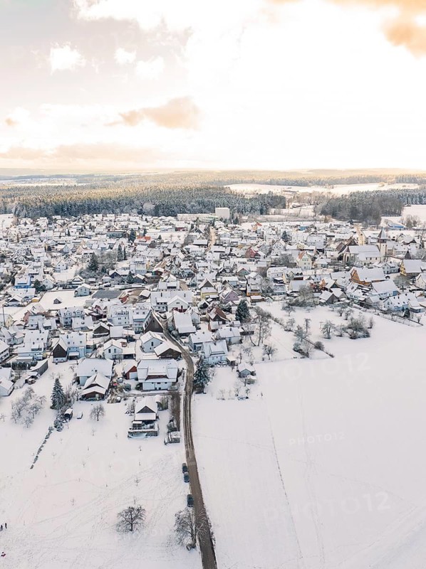 Village in the snow, surrounded by fields under a cloudy sky with sunlight, Calw, Altburg, district Calw, Black Forest, Germany