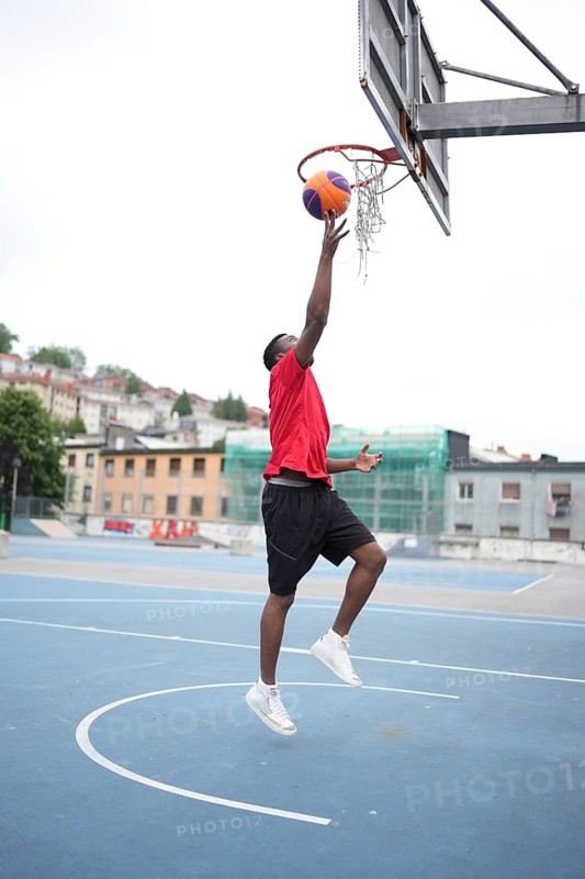 African american basketball player umping and scoring training in an outdoor urban court