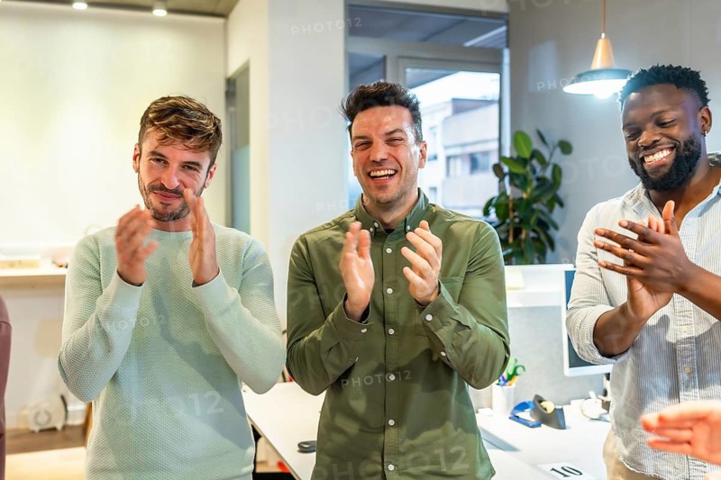 Multi ethnic business team clapping hands, celebrating success in a modern office, showing teamwork, achievement, and positive work environment