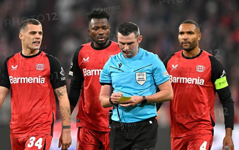 Referee Michael Oliver (ENG) notes yellow card yellow caution Granit Xhaka Bayer 04 Leverkusen (34) Edmond Tapsoba Bayer 04 Leverkusen (12) Jonathan Tah Bayer 04 Leverkusen (04) UEFA Champions League Allianz Arena, Munich, Bavaria, Germany