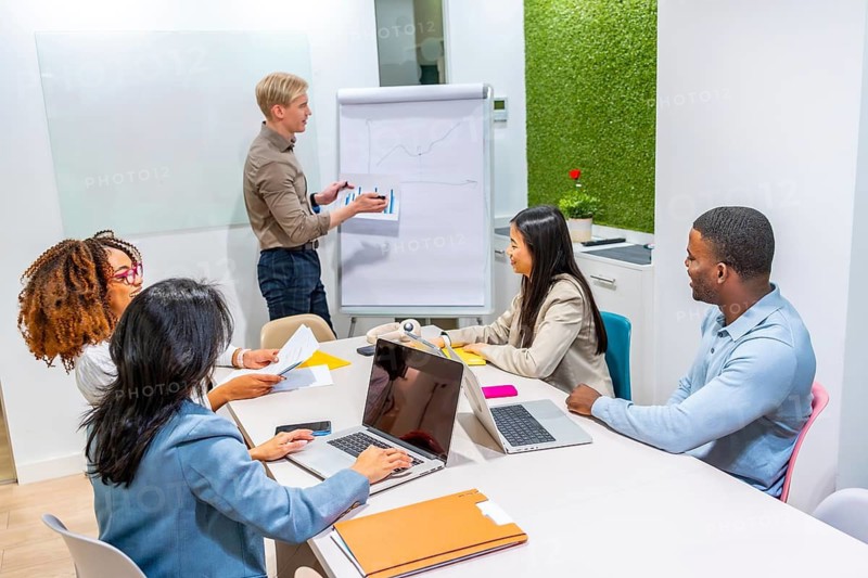 Diverse colleagues collaborating in a modern coworking space, analyzing charts and discussing growth strategies during a productive business meeting