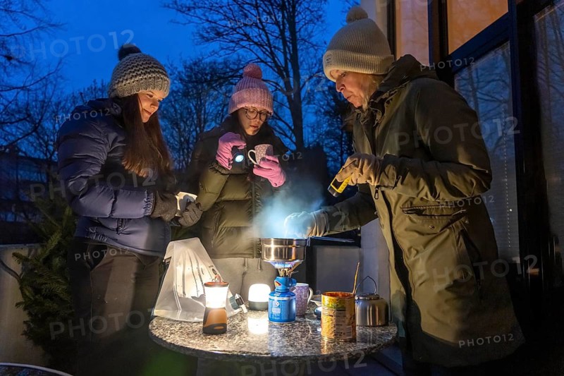 Symbolic picture blackout, extensive, prolonged power failure, in private surroundings, without electricity, heating, water, cooking, heating food and water with a gas-powered camping stove, on the balcony