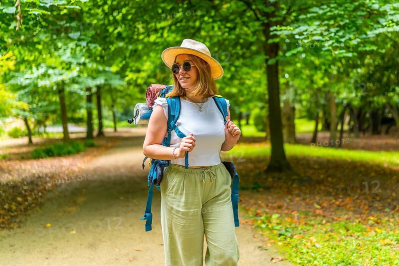 Frontal view of a caucasian adult woman carrying backpack while walking among trees in the forest