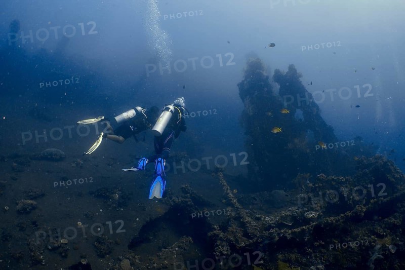 Two divers explore a shipwreck on the seabed in the deep blue surroundings of the ocean, dive site wreck of the USAT Liberty, Tulamben, Bali, Indonesia