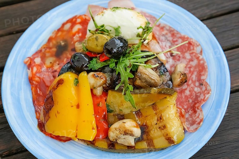 Mediterranean cuisine, grilled vegetables arranged on plates, mushrooms, mushrooms, red and yellow peppers, rocket, salami, black and green olives, Italian starter, antipasto misto, healthy cuisine, food photography, studio, Germany
