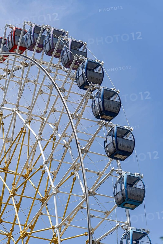 Captivating view of a colorful Ferris wheel towering against a bright blue sky, illustrating a day full of leisure and adventure in the cityâ€™s vibrant amusement park