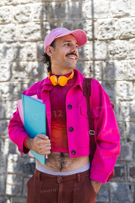A young Spanish man with a mustache, dressed in vibrant pink clothing, holds folders while enjoying a day out in urban Quito, Ecuador. Filled with urban lifestyle, casual fashion, and self-expression, resonating with LGTBIQ+ themes