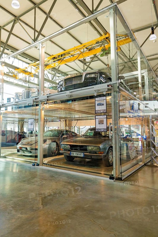 Several cars illuminated in a glass garage with industrial design and daylight, Motorworld Böblingen, Germany