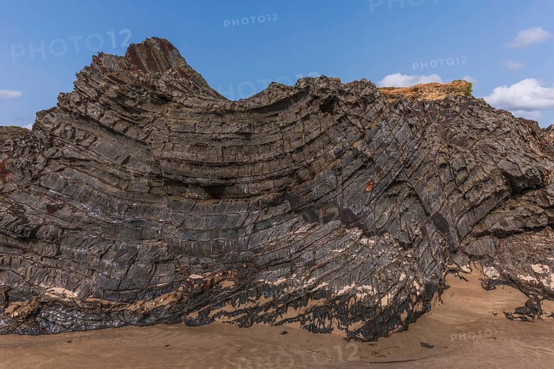 A rock with many holes and caves. Strange shapes in volcanic rock. Crozon, Brittany, Finistere, France