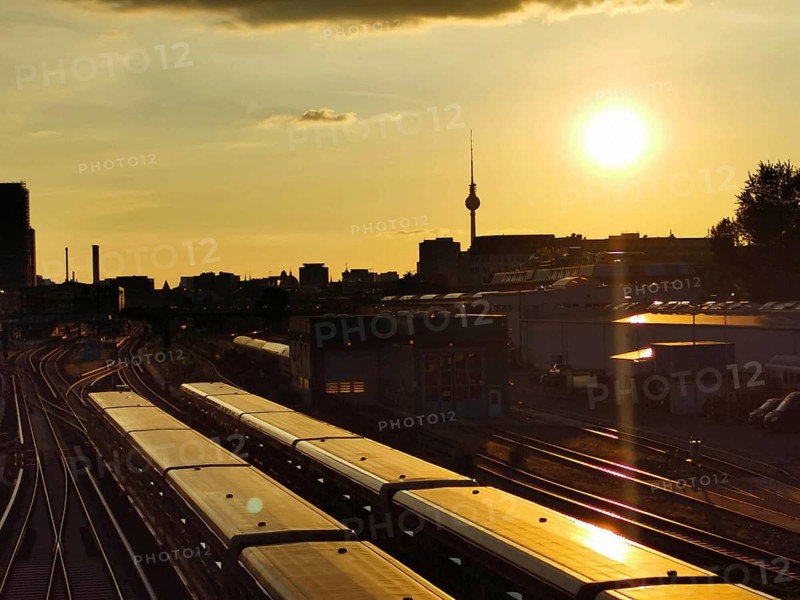 Sunset over train tracks with urban silhouette and Berlin TV tower in the background, Berlin