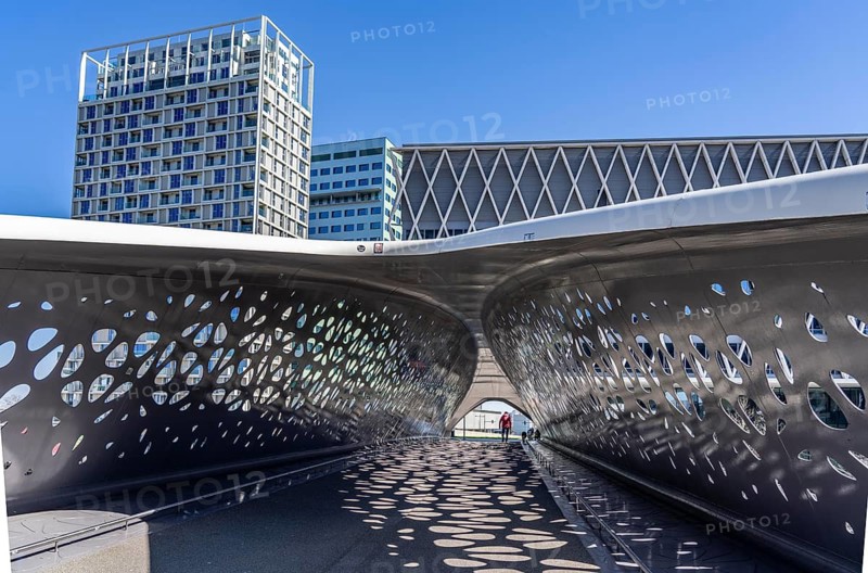 The Parkbruk, cycle and pedestrian bridge in the city centre of Antwerp, crosses a multi-lane city centre road, with tram lines, and thus connects two lively city districts Kop Spoor Noord and Eilandje, light effects by the sun, on the roadway, Belgium