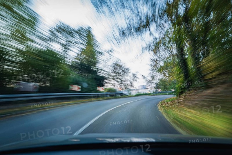 A winding road with trees in the background, conveying speed and movement, symbolised by drink-driving