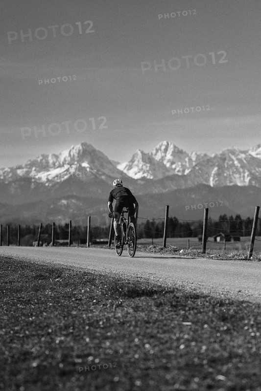 Road bike rider in spring near Halblech in the Allgäu in front of a picturesque backdrop of the Alps, Bavaria, Germany