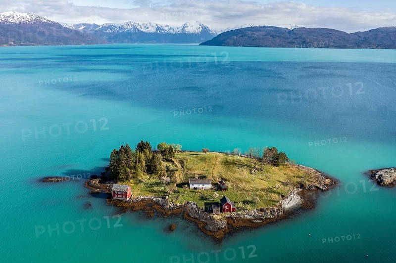 Aerial view of typical red houses on an island in the Hardangerfjord, mountain range in the back, near Strandebarm, Hordaland, Norway
