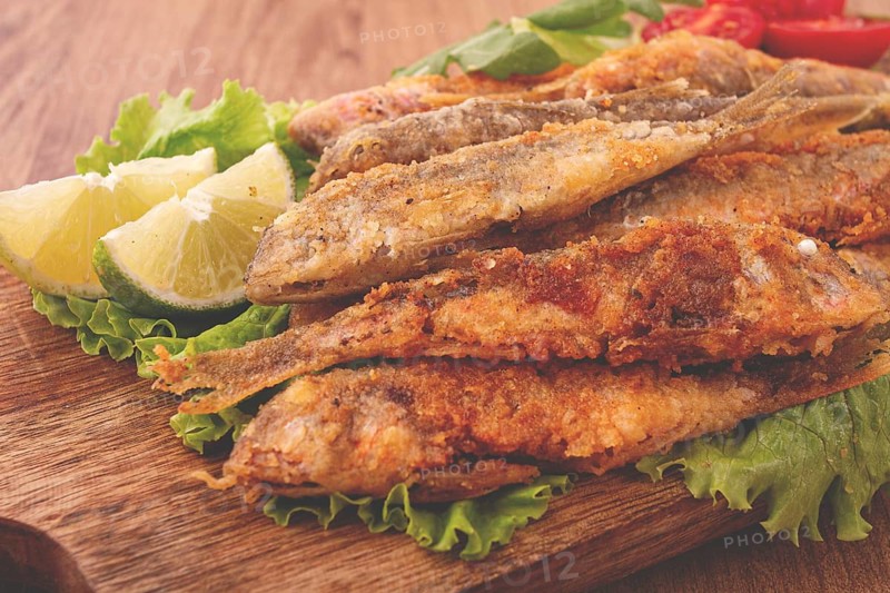 Fried crispy red mullet fish, on a wooden chopping board, with lime, no people