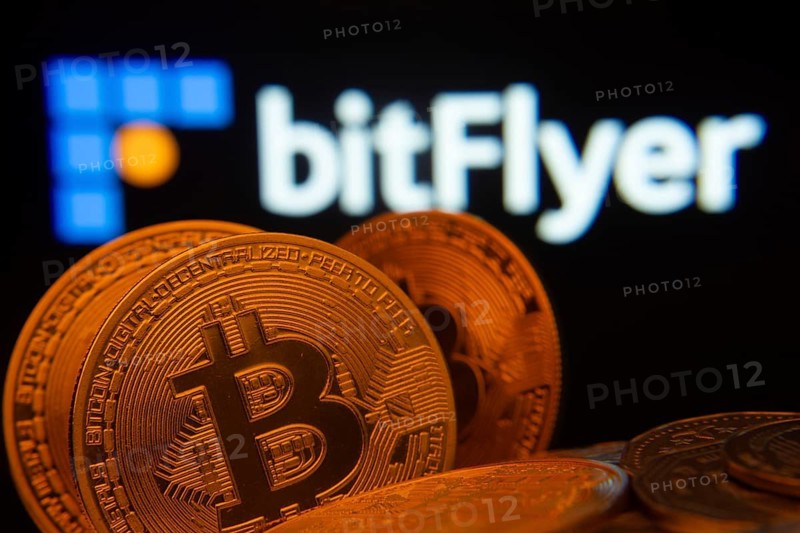 Dhaka, Bangladesh- 02 June 2025: Close-up of Bitcoin coins with the Bitflyer logo visible on a screen in the background