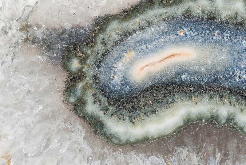 Macro photograph of Brazilian quartz with a central clay tube inclusion, surrounded by vibrant agate layers and an outer coating of sparkling quartz crystals, showcasing intricate details