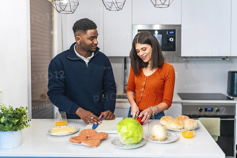 Young multiethnic couple preparing burgers for dinner, enjoying their time together in a modern and bright kitchen