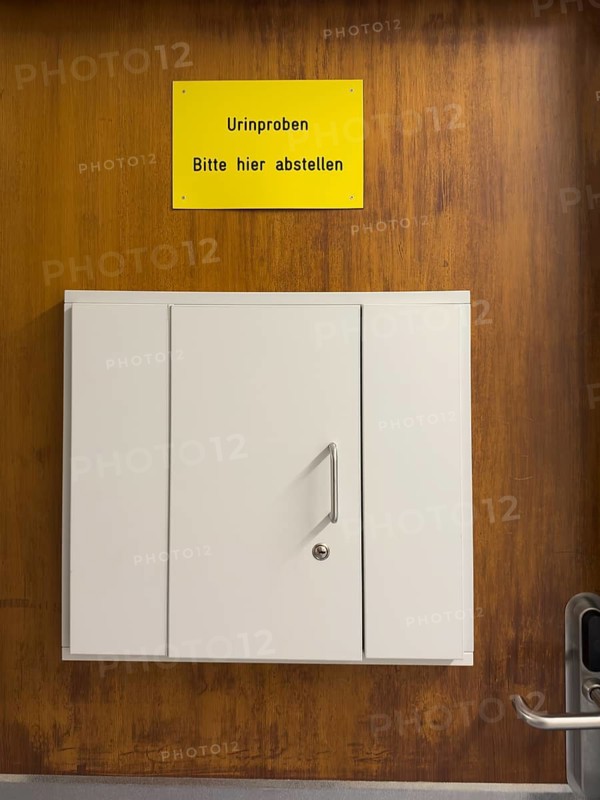 Door with sign that says leave urine samples here including a small cabinet, Germany