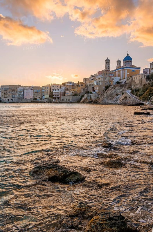 View of the village with the Greek Orthodox church of Agios Nikolaos, Asteria Beach, at sunset with atmospheric clouds, Ermoupoli, Syros, Cyclades, Greece