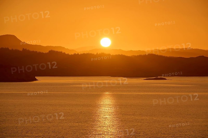 Atmospheric landscape scene at sunrise, calm sea and silhouetted islands in the twilight, autumn, Bergen, North Sea, Norway