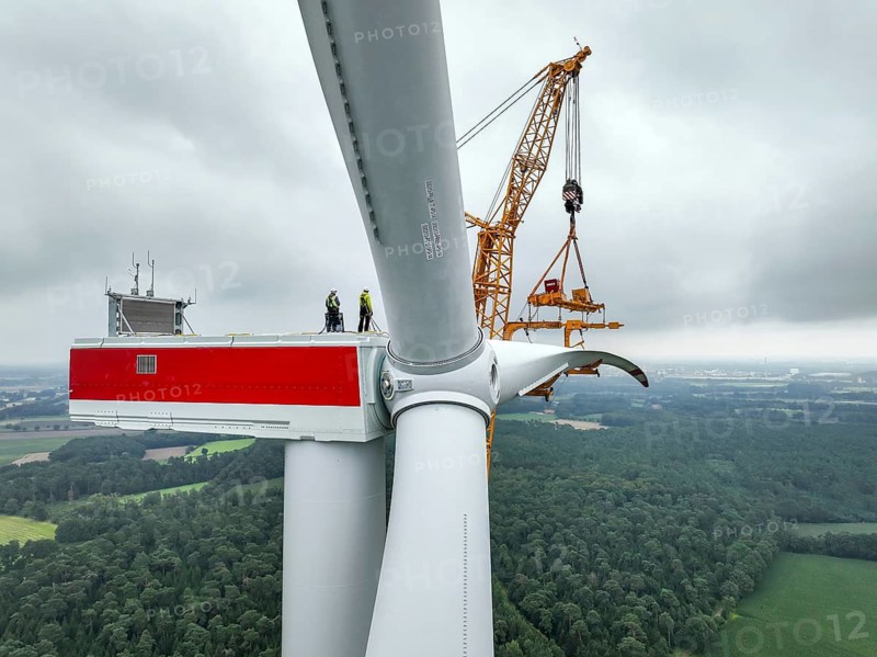 Dorsten, North Rhine-Westphalia, Germany, construction of a wind turbine. A large mobile crane lifts a rotor blade to the nacelle on the tower. Here, the blade is mounted directly on the motor hub. Große Heide wind farm
