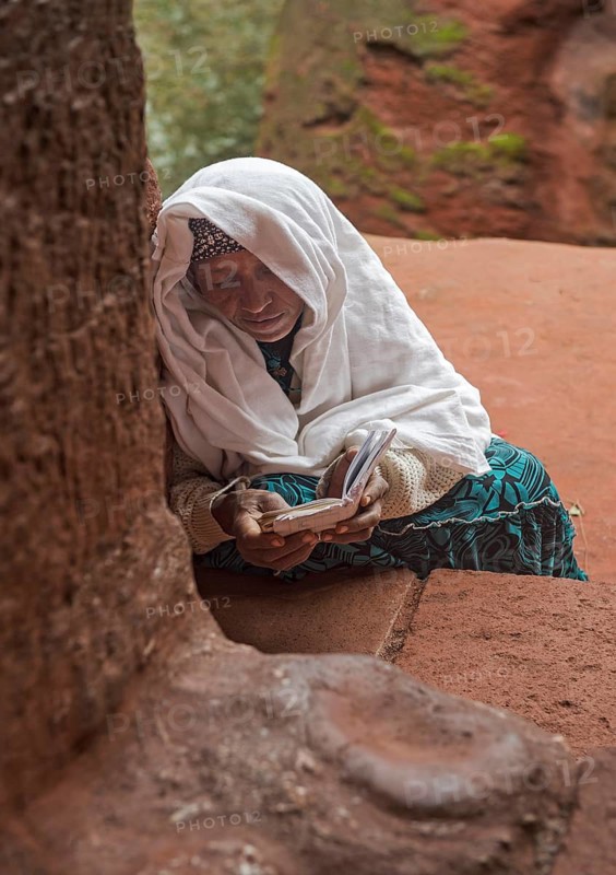Ethiopian Orthodox believers absorbed in prayer at the entrance to the rock-hewn church of Biete Gabriel-Rufael, Lalibela, Ethiopia