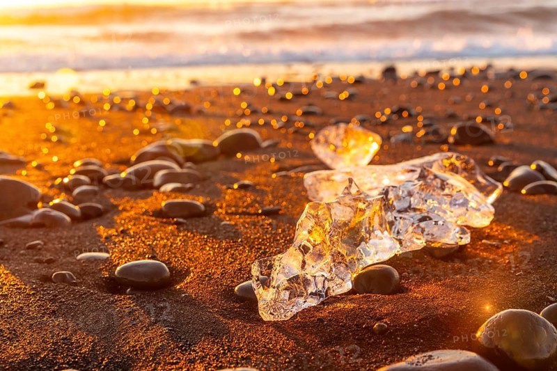 Ice and stones at sunrise with ice on Diamond Beach next to Jokulsarlon in winter in Iceland