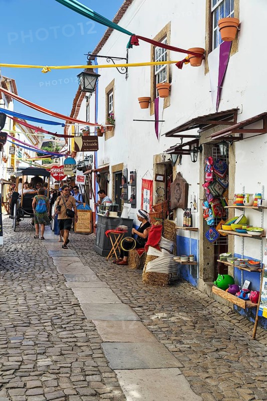 Picturesque alley with shops and pedestrians, tourists in the medieval village of Óbidos, Portugal