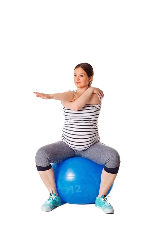 Pregnancy exercise concept, pregnant woman doing stretching exercises with exercise ball isolated on white background
