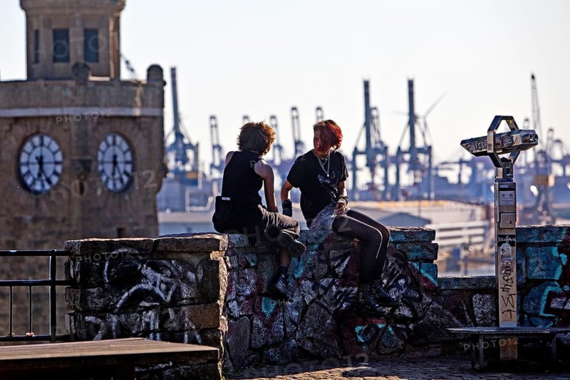Two young woman on the viewing platform Auf dem Stintfang with Hamburg harbour and the St. Pauli jetties in the background, Germany