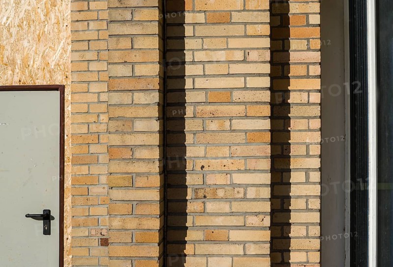 Old building with brick walls and a door covered with OSB panels