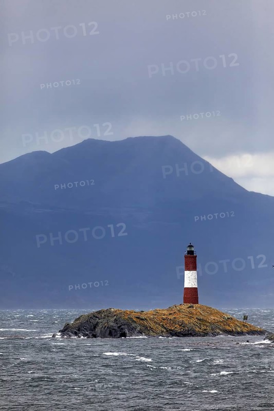Lighthouse on a small rocky island in front of a cloudy mountain background, The lighthouse in the Beagle Channel near Ushuaia in Argentina