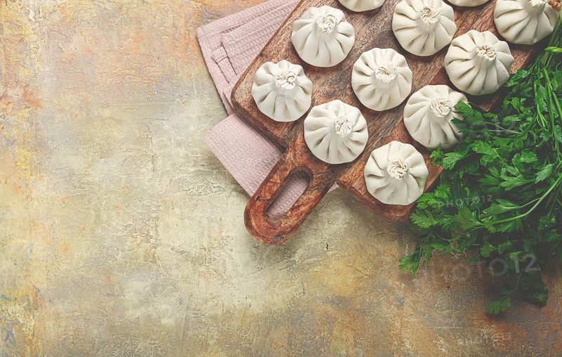 Freshly frozen raw khinkali, on a wooden chopping board, top view, Georgian cuisine, no people