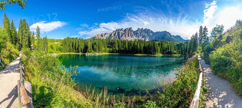 Emerald waters reflecting latemar mountain range, creating breathtaking scenery at lake carezza, a popular tourist destination in the italian dolomites
