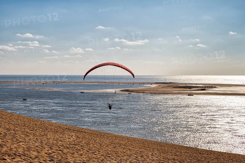 Paraglider flying from dune towards the Atlantic Ocean, Dune du Pilat, Banc d'Arguin nature reserve, Arcachon basin, La Teste-de-Buch, Gironde, Aquitaine, France