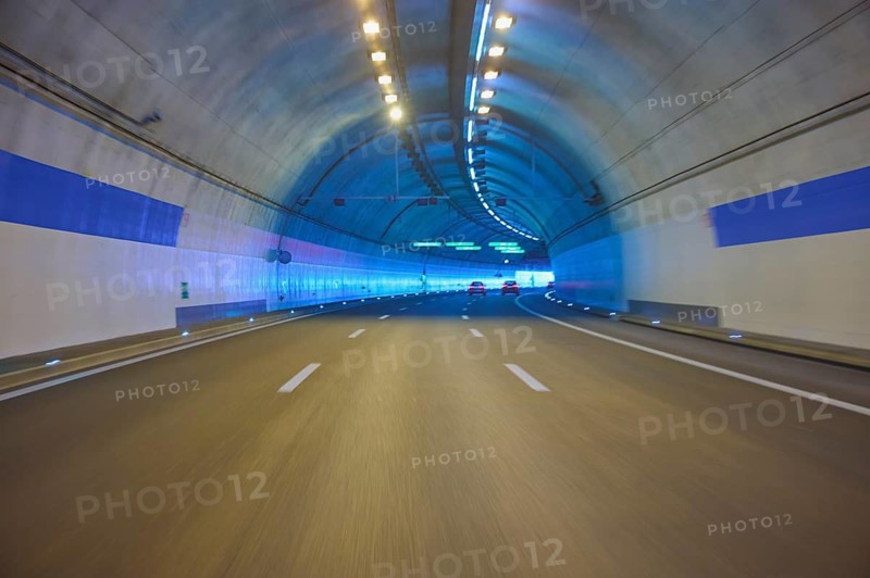 Modern, well-lit motorway tunnel with blue illuminated walls and a clear asphalt road, Zurich, Switzerland
