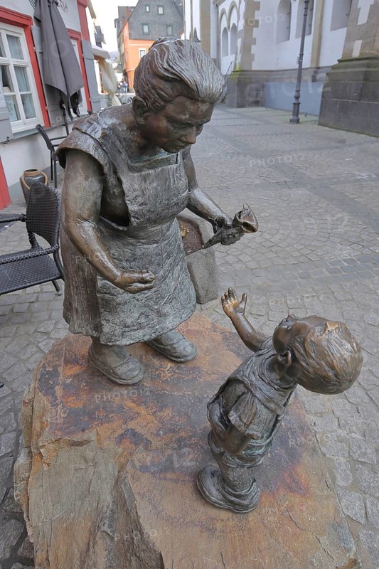 Schnuggel Elsje sculpture by Jutta Reiss, saleswoman giving ice cream cone to child, stretching out, selling ice cream, symbol of joy, giving, receiving, gift, gesture, market woman, modern art, bronze sculpture, life-size, Boppard, Upper Middle Rhine Valley, Rhineland-Palatinate, Germany