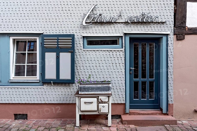 Residential house clad with wooden shingles, old oven for decoration in front of design hotel Die Träumerei with lettering träum' weiter..., narrow alley, historic old town, Michelstadt, Odenwald, Hesse, Germany